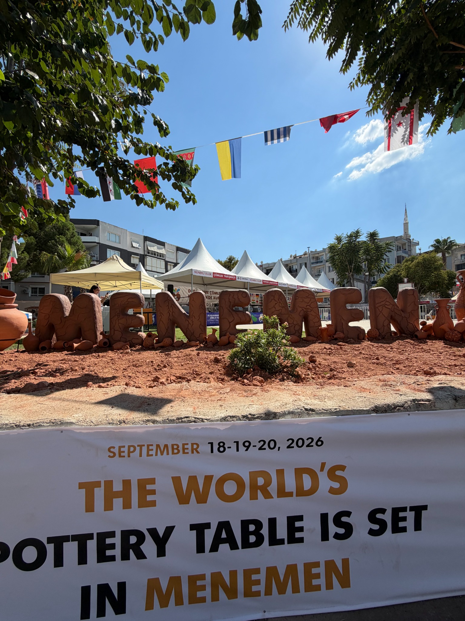 Daniel beneath the Menemen festival installation and international flags