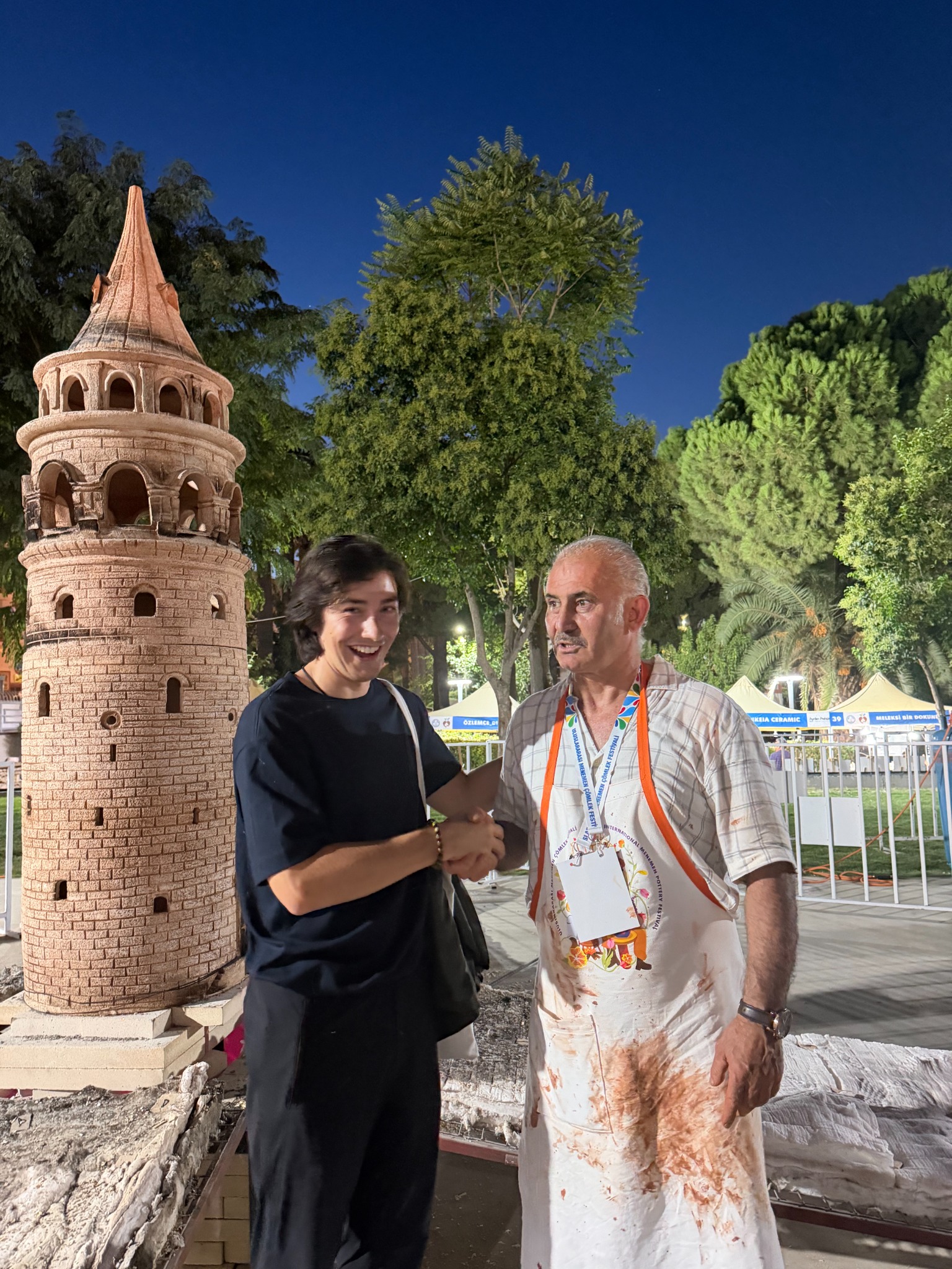 Daniel shaking hands with a ceramic artist beside the completed tower