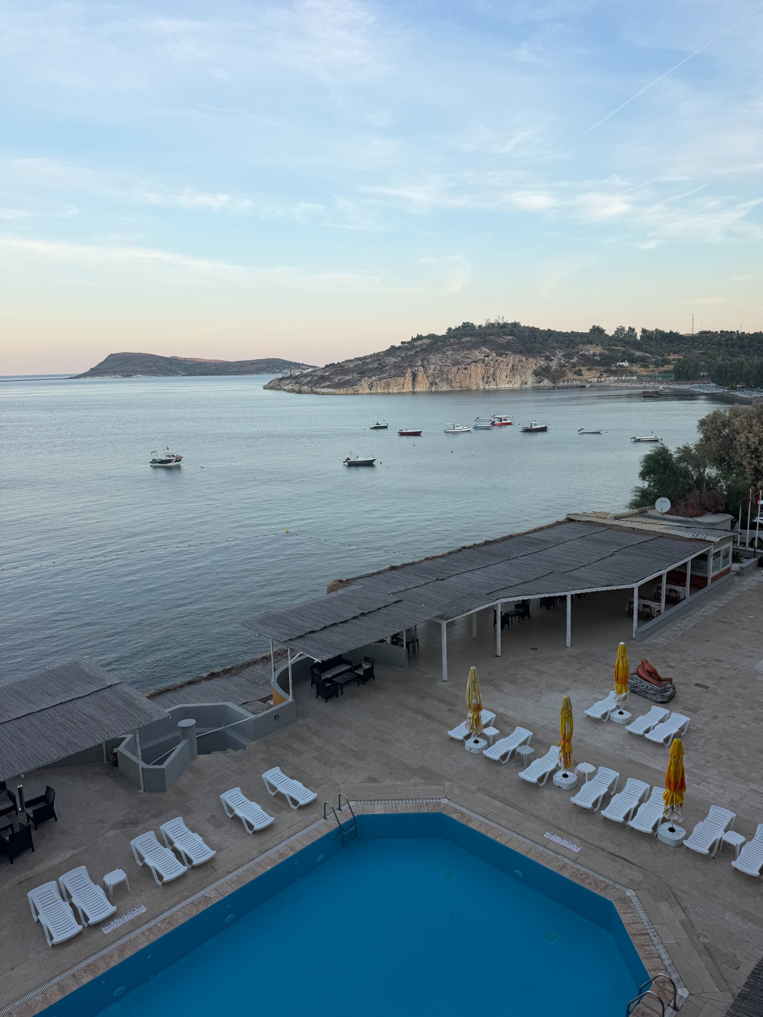A calm Aegean bay with small boats at dusk